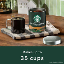 Starbucks instant coffee can with metal lid and two glass mugs on cloth