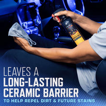 Hand spraying a dark-blue trigger bottle onto a car seat for interior detailing