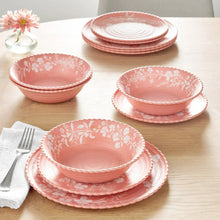 Pink floral melamine bowls and plates set on tabletop, scalloped rims and white print