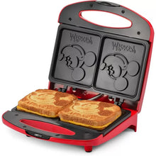 Red dual sandwich maker with two sandwiches toasting on the plates
