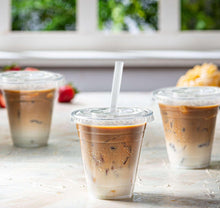 Disposable clear plastic coffee cups with lids and white straws, iced drinks