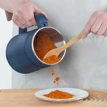 Blue electric grinder tipping to pour ground spice from stainless chamber