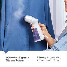 Handheld garment steamer steaming a blue shirt front