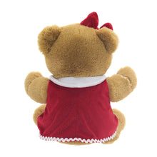 Brown teddy bear plush facing away, red dress with white trim and small paw details