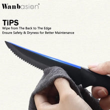 Black steak knife with serrated blade and black handle held in a hand with cloth