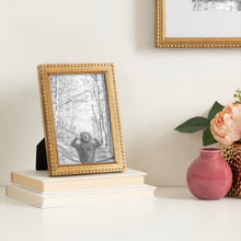 Gold beaded tabletop picture frame with black-and-white portrait print