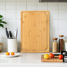 Bamboo cutting board on countertop with rectangular shape and handle cutouts, natural finish