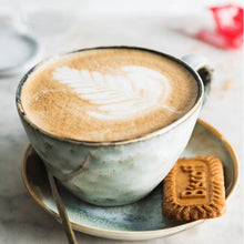 Coffee cup with latte foam and Lotus Biscoff biscuit