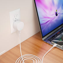 White USB-C wall charger plugged in beside laptop with USB-C cable