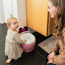 Pink potty training toilet with white seat and black top handles