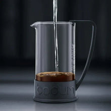 Glass French press coffee maker with dark base and metal plunger rod
