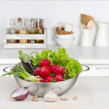 Stainless steel perforated colander with two side handles, filled with vegetables