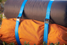 Blue cam buckle lashing straps securing an orange bag with a rolled item