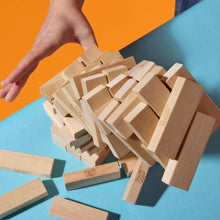 Pile of light wood Jenga blocks with a hand reaching toward the pieces