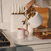 Pink floral stoneware mug with pink interior as liquid pours into it