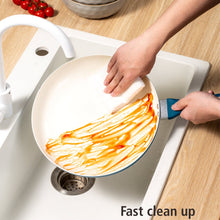 Nonstick frying pan with cream cooking surface and teal handle while food is spread by hand.