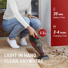 Handheld cordless vacuum in red and black being used on a carpeted floor