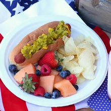 White paper dinner plate with mixed fruit and sliced sausage