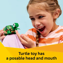 Green turtle building toy with posable head and mouth, held by a child
