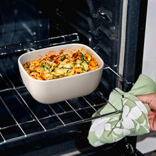 Taupe stoneware bake dish with cheesy casserole on oven rack