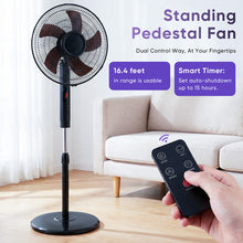 Black standing pedestal fan with remote control in hand