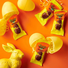 Assorted Reese’s snack-size peanut butter eggs in yellow plastic basket and wrappers