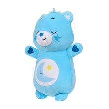 Blue plush bear toy facing left with moon belly emblem, star patch, and winged shoulder hearts