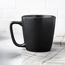 Matte black stoneware mug resting on checkered cloth