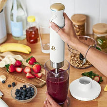 Cordless immersion blender in white icing with whisk attachment over a blender cup