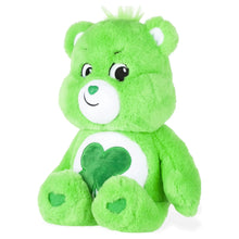 Green plush teddy bear sitting with white muzzle and clover-shaped belly emblem