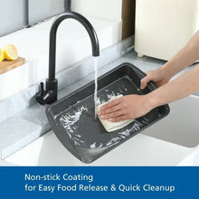 Non-stick bakeware pan being washed in sink with water and sponge for cleanup