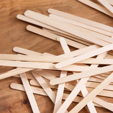 Natural wooden craft sticks stacked together in a close-up.