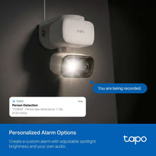 Wall-mounted security camera in white housing with bright spotlight illumination