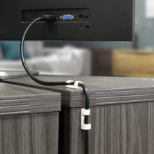 White adhesive cable clips securing a black cable along a desk edge.