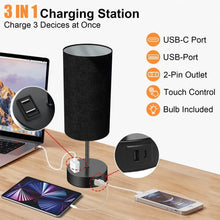 Black table lamp with fabric shade and base panel featuring USB-C, USB, and 2-pin outlet.