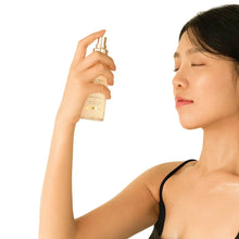 d'Alba First Spray Serum bottle held in hand above model’s face