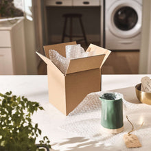 Small bubble cushioning wrap pieces and roll in open cardboard box