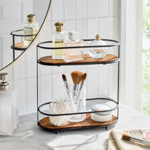 Two-tier vanity organizer with black metal frame, round wood shelf, and brush cup