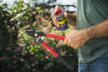 WD-40 spray can with red straw nozzle applying lubricant to an outdoor valve