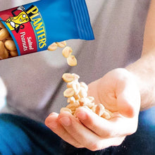 Planters salted nuts pouch tipped, cashews spilling into open hand