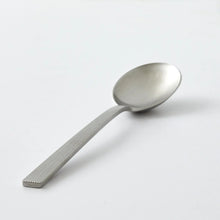 Satin stainless steel spoon with ribbed handle and oval bowl close-up