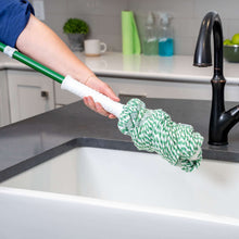 Twist mop with green handle and green-and-white yarn head held over sink