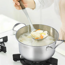 Large stainless steel stockpot with loop handles, glass lid, and simmering contents