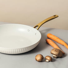 White nonstick ceramic fry pan with gold handle on countertop