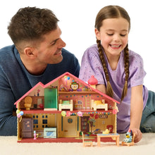 Toy playset house with pink roof and interior rooms, held by two kids