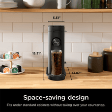 Black single-serve pod coffee brewer with tall brewing unit and countertop cups.