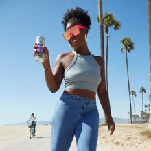 V8 Energy drink can held in hand; person wearing a light blue crop top and jeans