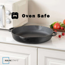 Black cast iron frying pan with two loop handles on a kitchen stove