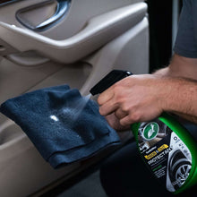 Car interior detailing: dark cloth being sprayed with TurtleWax protect bottle