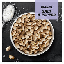 In-shell salt and pepper pistachios in a white bowl with scattered seasoning